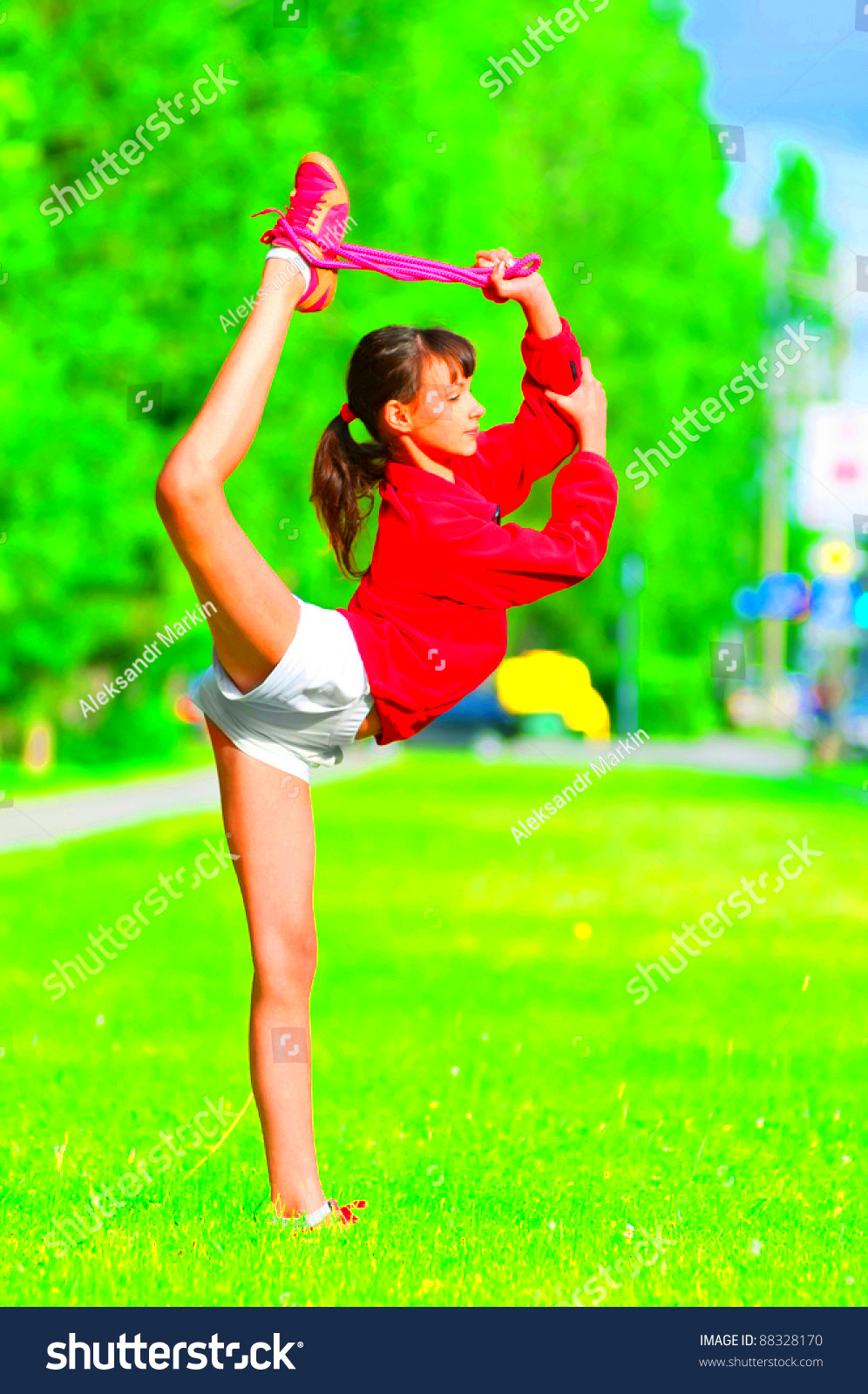 Teenage Girl Doing Stretching Exercise On Green Grass At Park Yoga